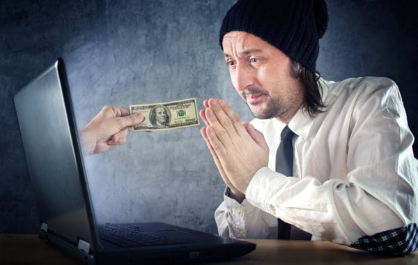człowiek przed laptopem modli się o pieniądze